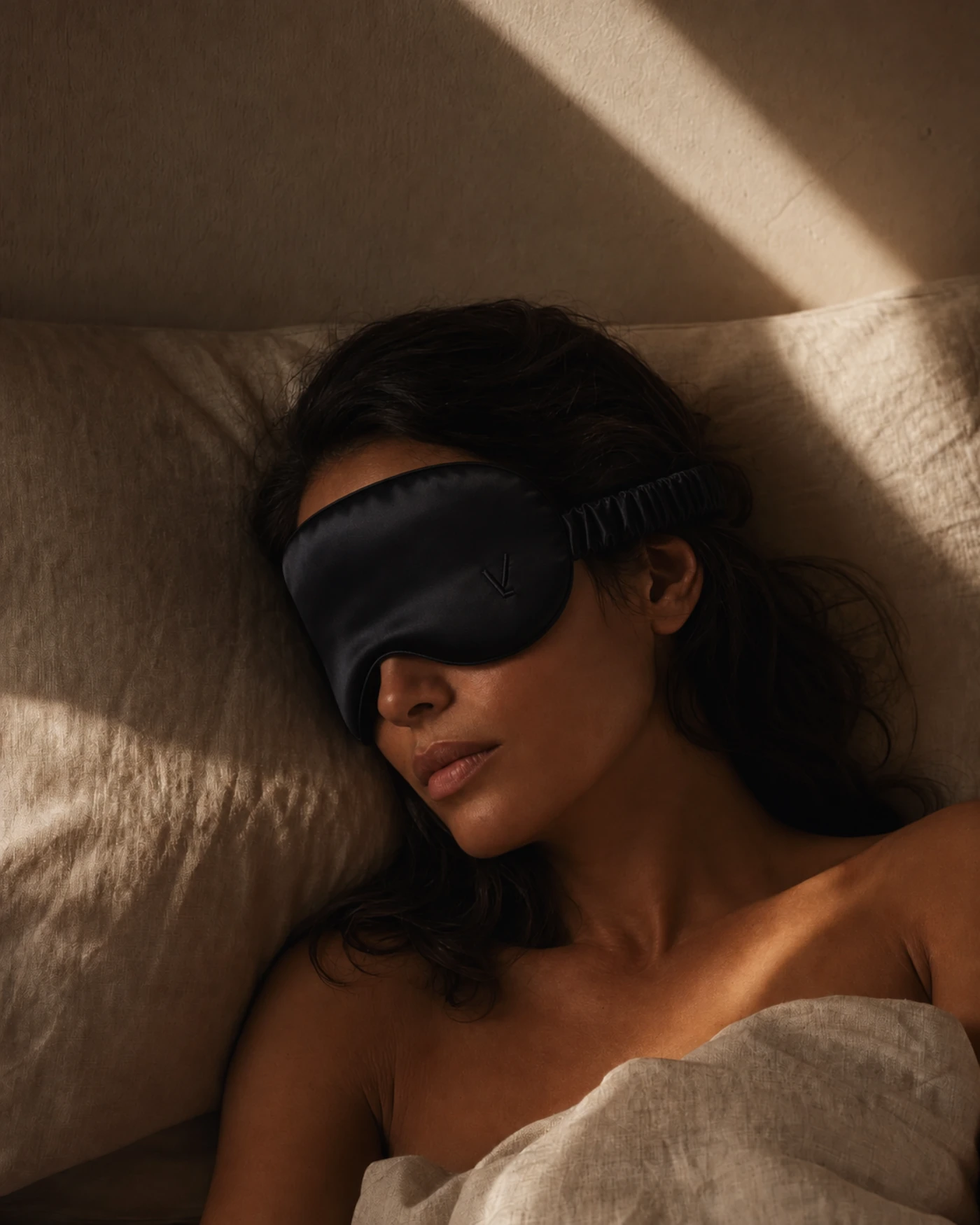 Una mujer durmiendo de costado con VEIL puesto, mientras la luz de la mañana cruza la pared detrás